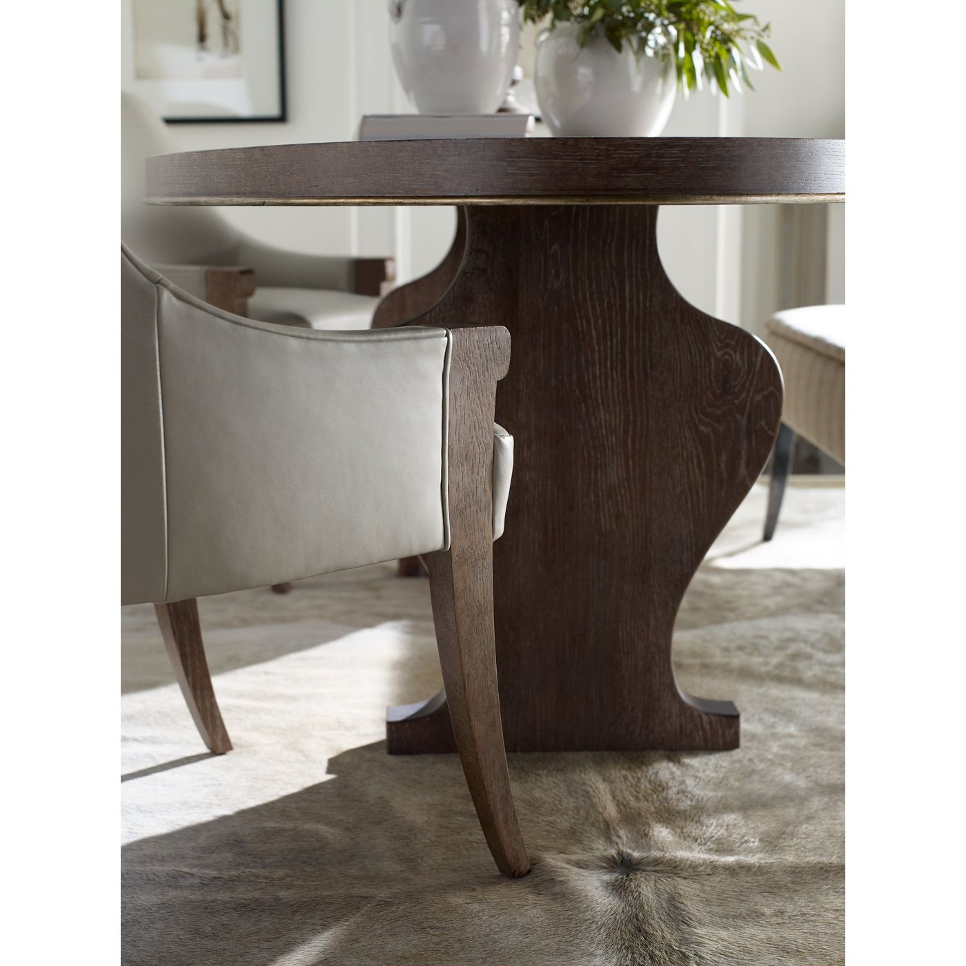 Oak pedestal dining table and leather chair on a hide rug